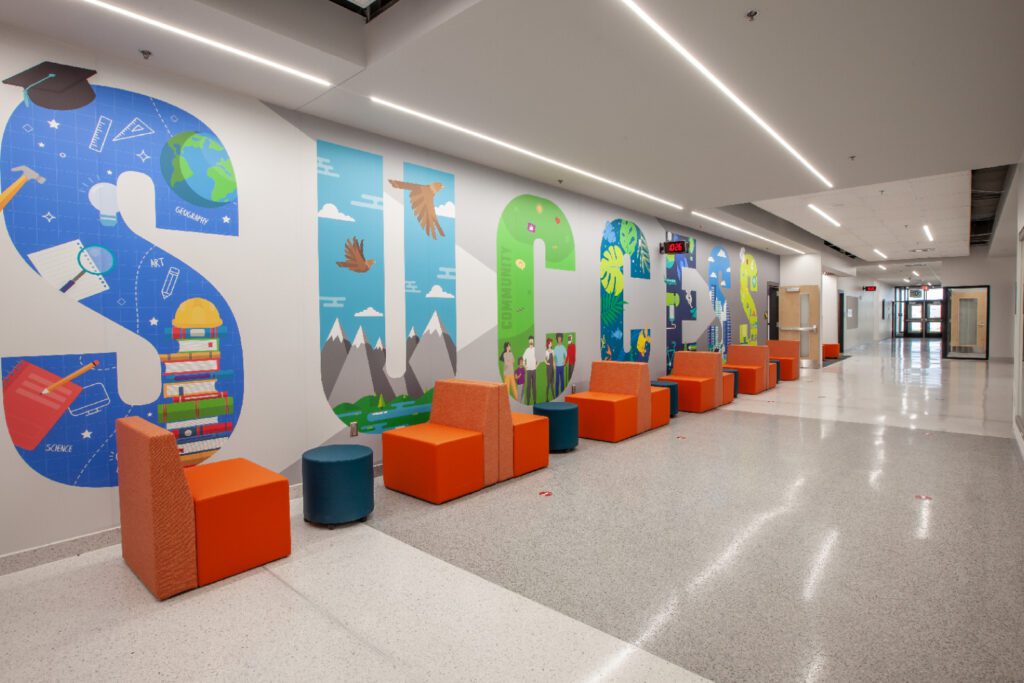 A hallway with colorful chairs and a mural on the wall.